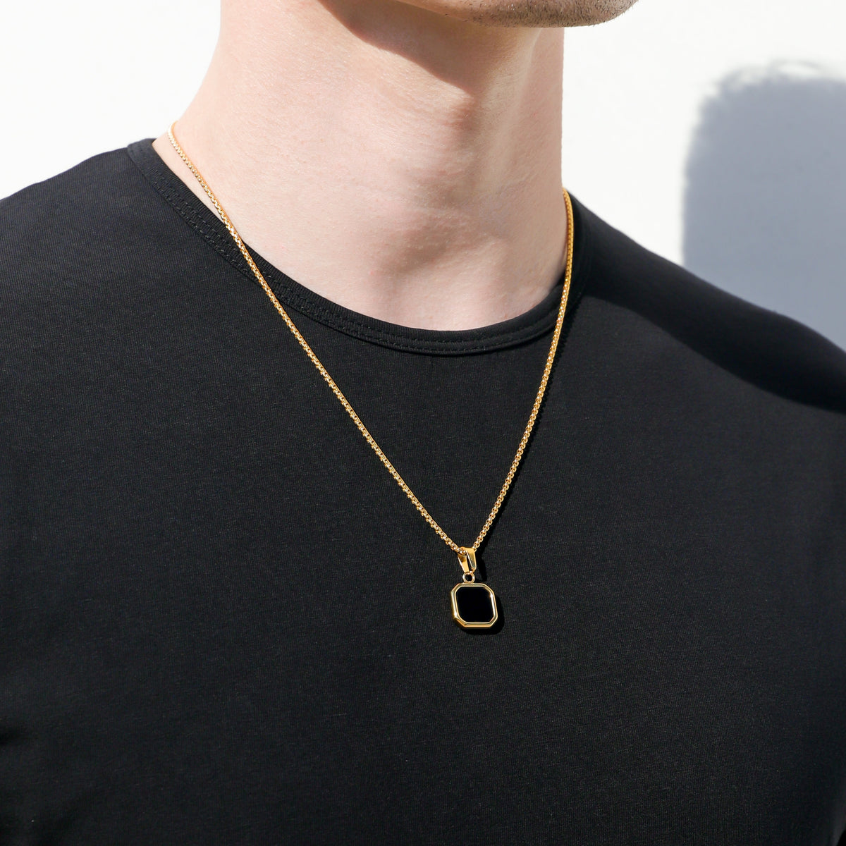 Gold-tone pendant necklace set with square black onyx charm, side view on neck