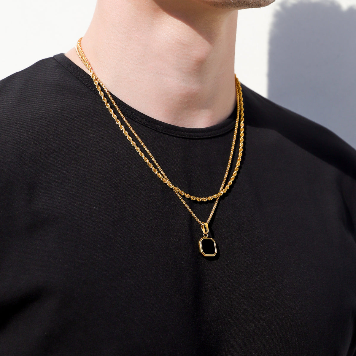 Gold-tone two-layer pendant necklace with square black onyx charm on black shirt