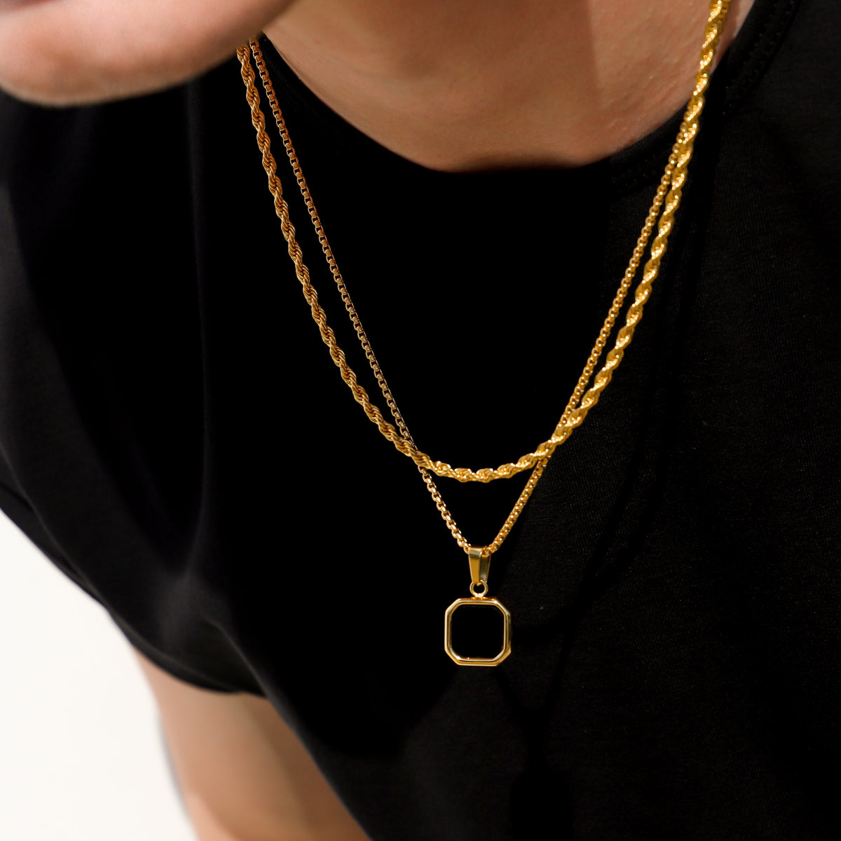 Gold-tone two-layer necklace with square black onyx charm, close-up on neckline