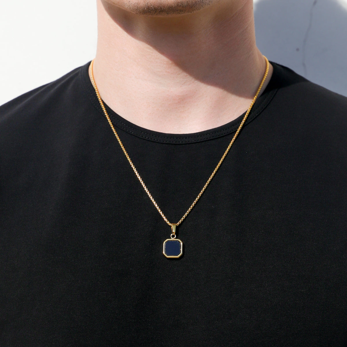 Gold-tone square black onyx pendant necklace set, two chains over dark shirt