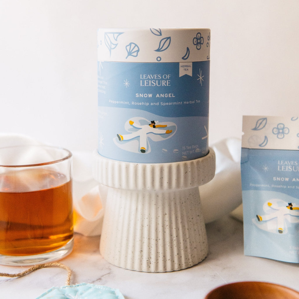 Blue herbal tea tins with winter labels beside a cup of amber tea