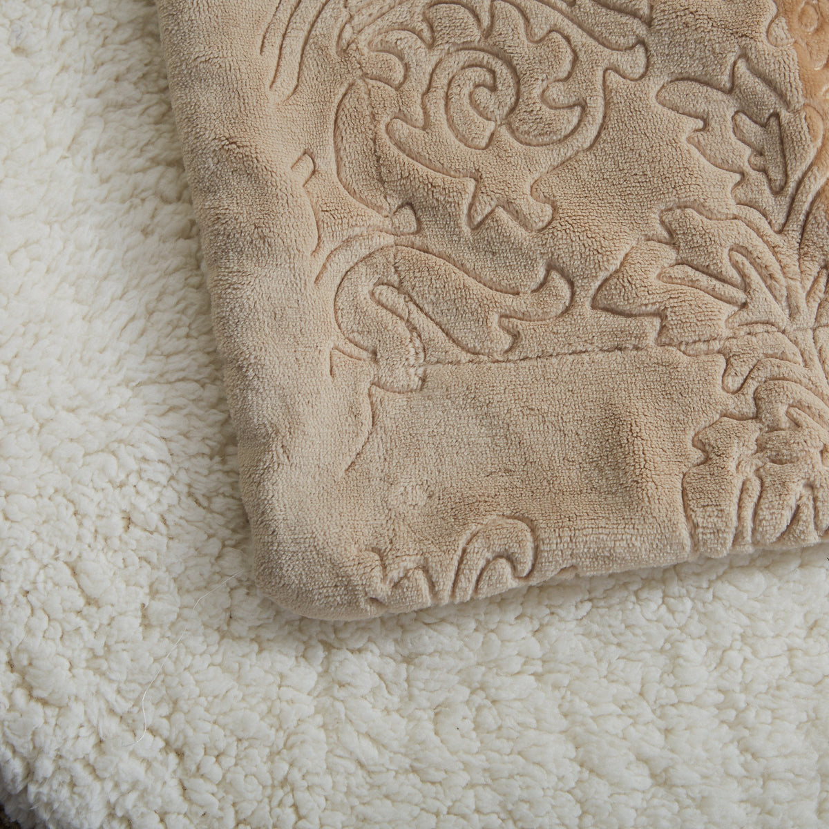Embossed beige bubbly pattern on sherpa throw blanket, textured close-up