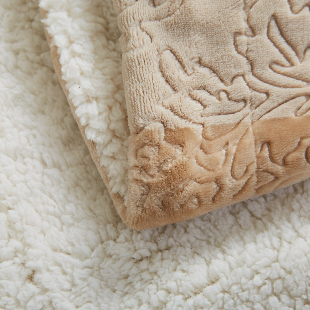 Close-up of beige sherpa throw blanket corner with embossed decorative design