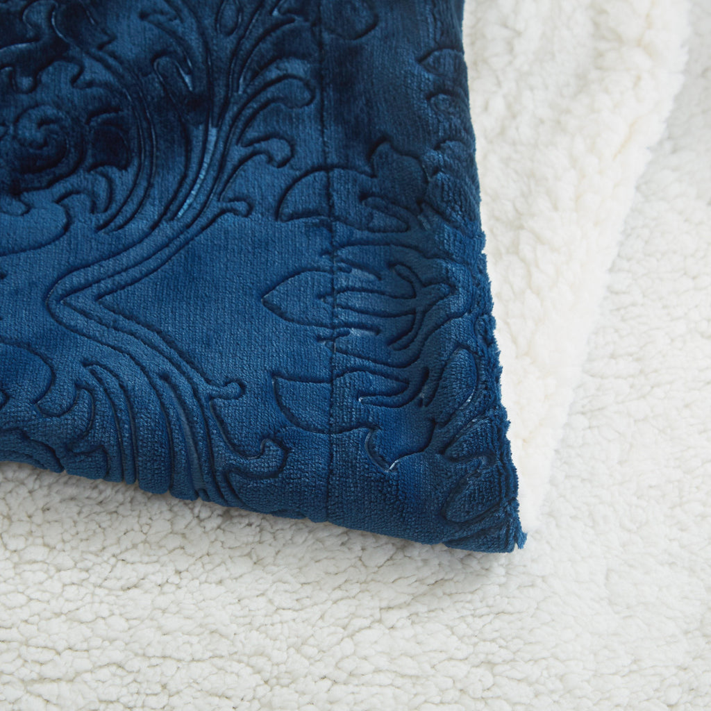 Tache night blue embossed throw blanket corner resting on white sherpa fleece