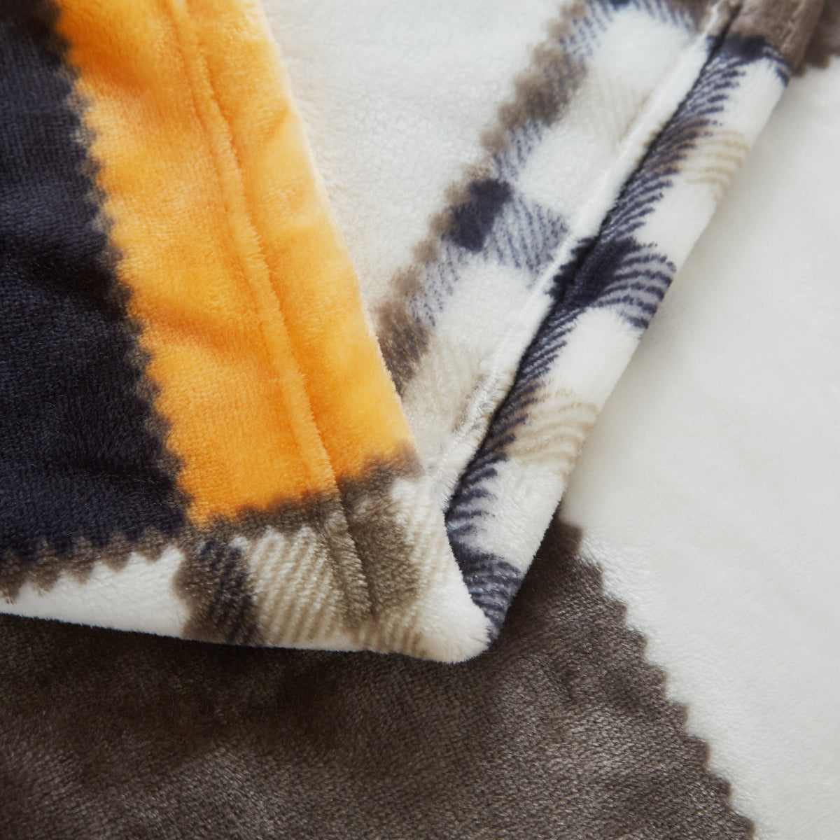Plaid fleece blanket edge with orange, dark brown, navy, and cream stripes