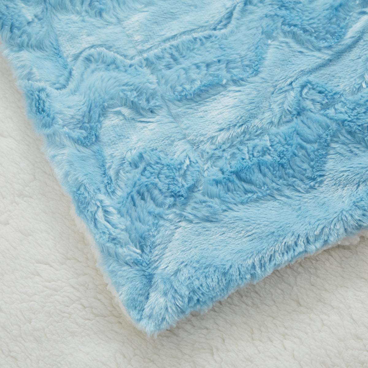 Blue faux fur throw blanket corner with cream underside visible