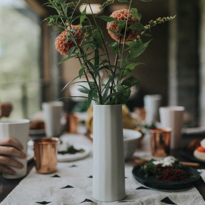 Handmade porcelain flower vase, silk white, on table with floral stems