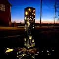 Solar steel luminary pillar light with glowing dandelion and grass silhouettes