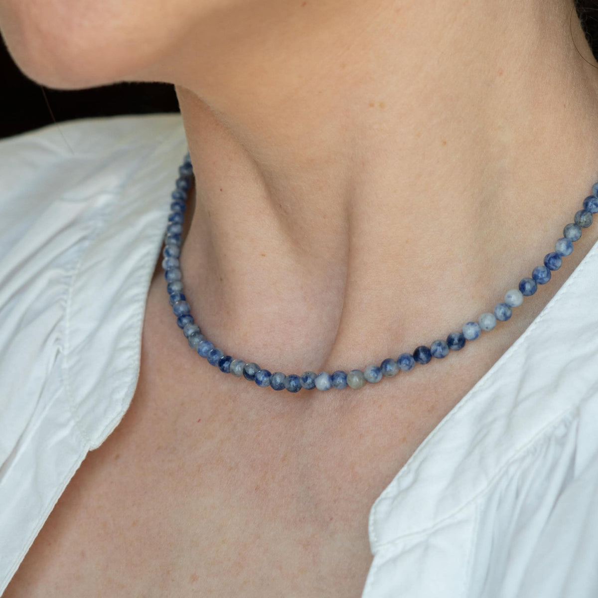 Blue beaded necklace on model neckline; navy and light-blue round beads