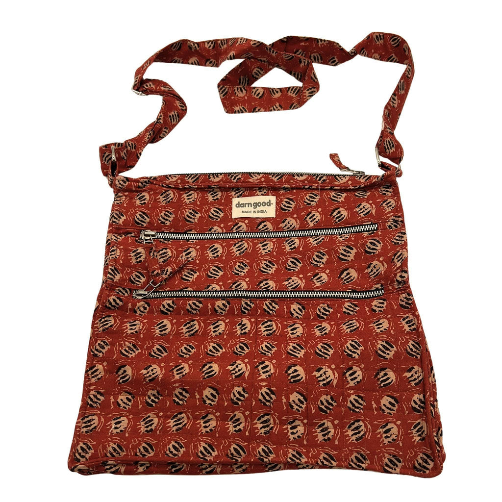 Patterned crossbody bag in rust orange with dark accents, top zip closure