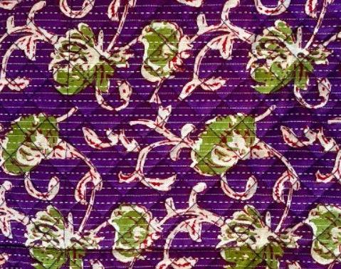 Purple patchwork fabric with green floral motifs and white dashed stitch lines