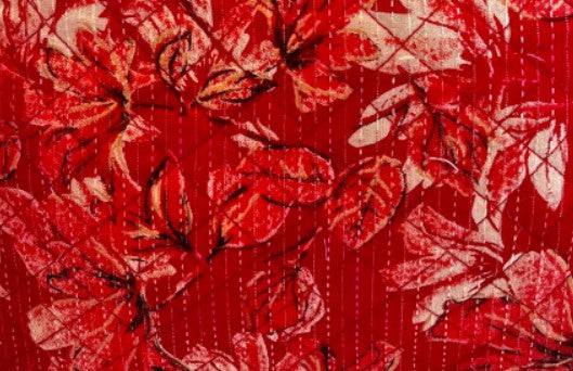 Red patchwork fabric with white leaf-and-stitch pattern across textured stripes