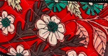 Red patchwork fabric with cream flower and leaf motifs and decorative stitchwork