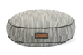 Round pet bed with gray chevron patterned fabric and a rectangular patch label