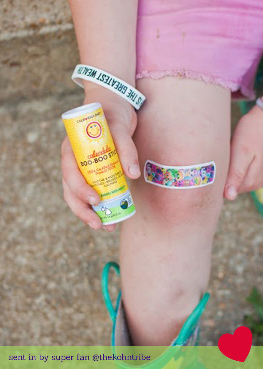 Boo-Boo stick held near knee, yellow balm tube and colorful bandage visible