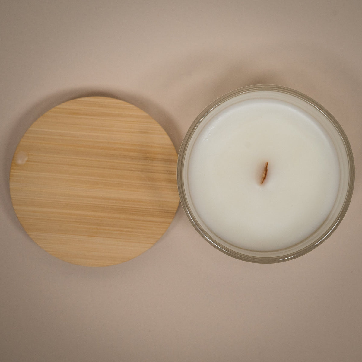 Glass candle jar with white wax and wick, with round bamboo lid and glass cover.