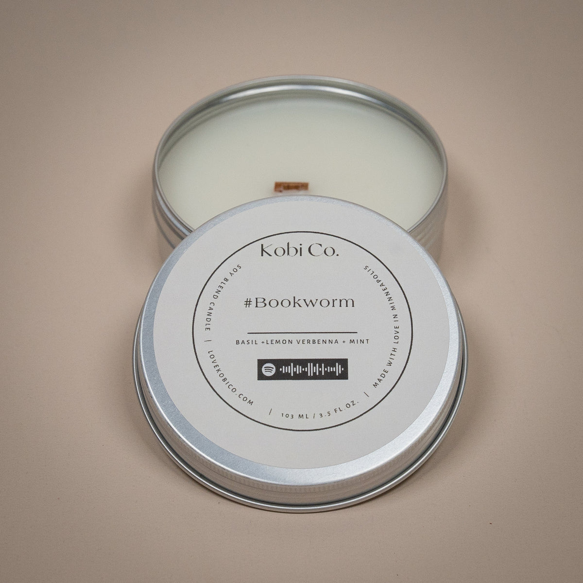 Bookworm candle tin with white wax and wick, round label 'Kobi Co. #Bookworm'.