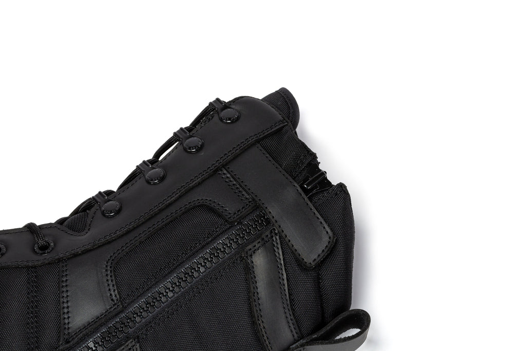 Men's black tactical boot upper close-up with lace loops and reinforced side stitching