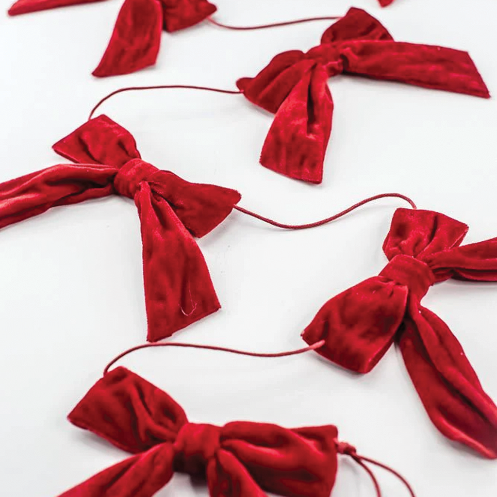 Close-up of red velvet bows with dangling tails on thin red string