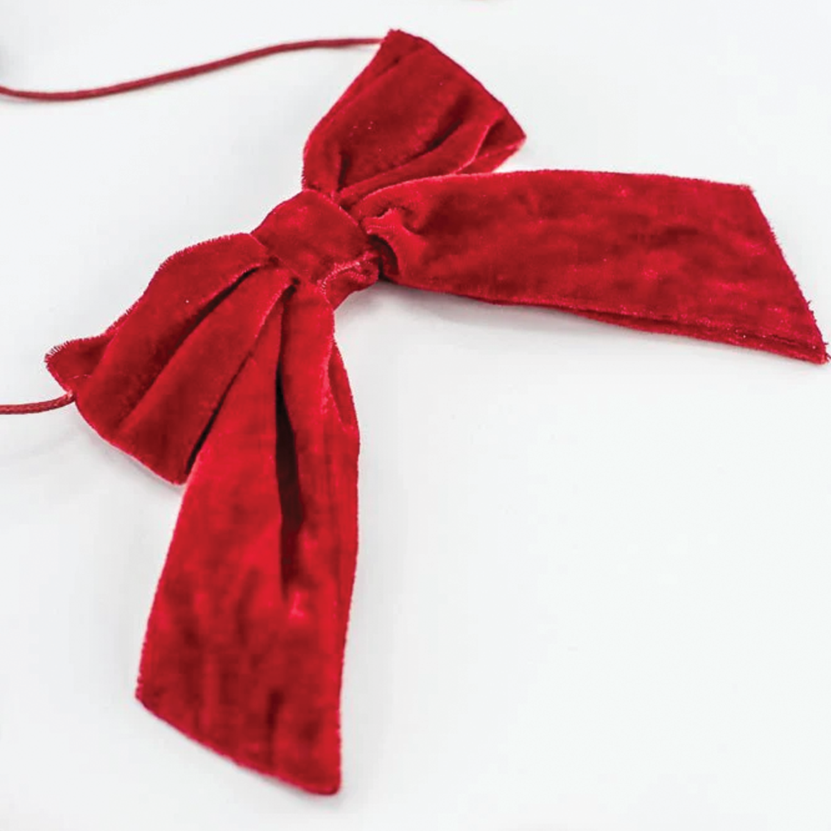 Single red velvet bow on a cord with short hanging ribbon tails