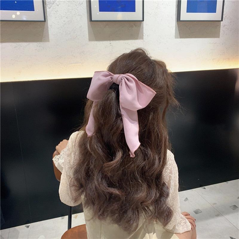 Light pink bowknot hair scrunchie with large bow and hanging ribbon ends.