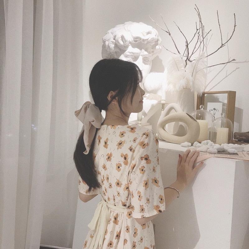 Cream bowknot hair scrunchie with long fabric tails on low ponytail