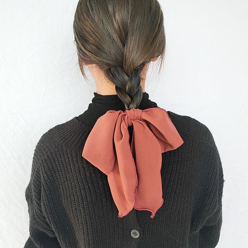 Rust orange bowknot hair scrunchie with tied bow and ribbon tails.