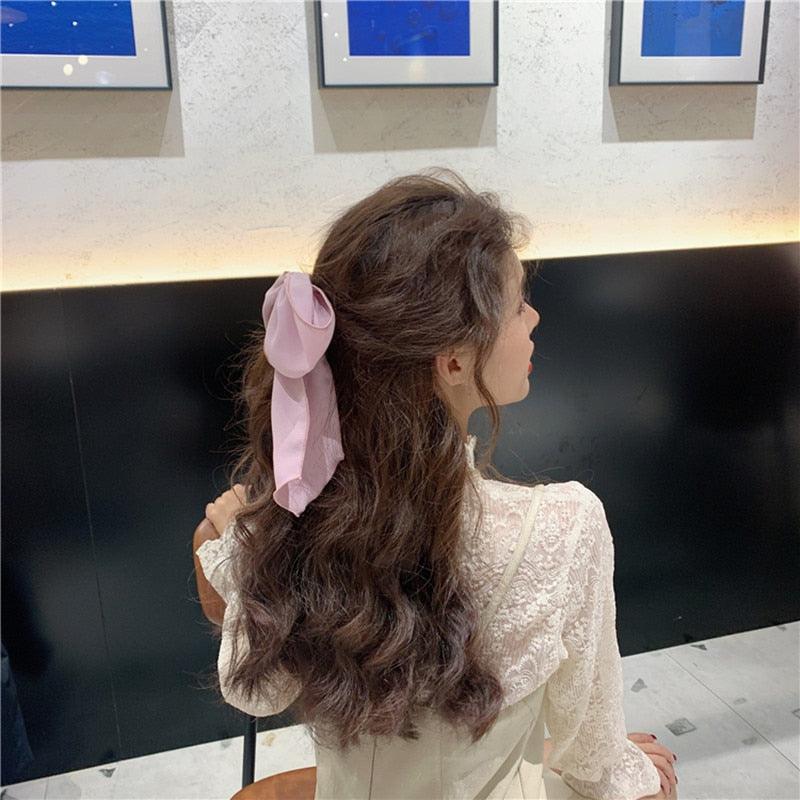 Pink satin bow hair scrunchie with elastic hair band, knotted on a ponytail