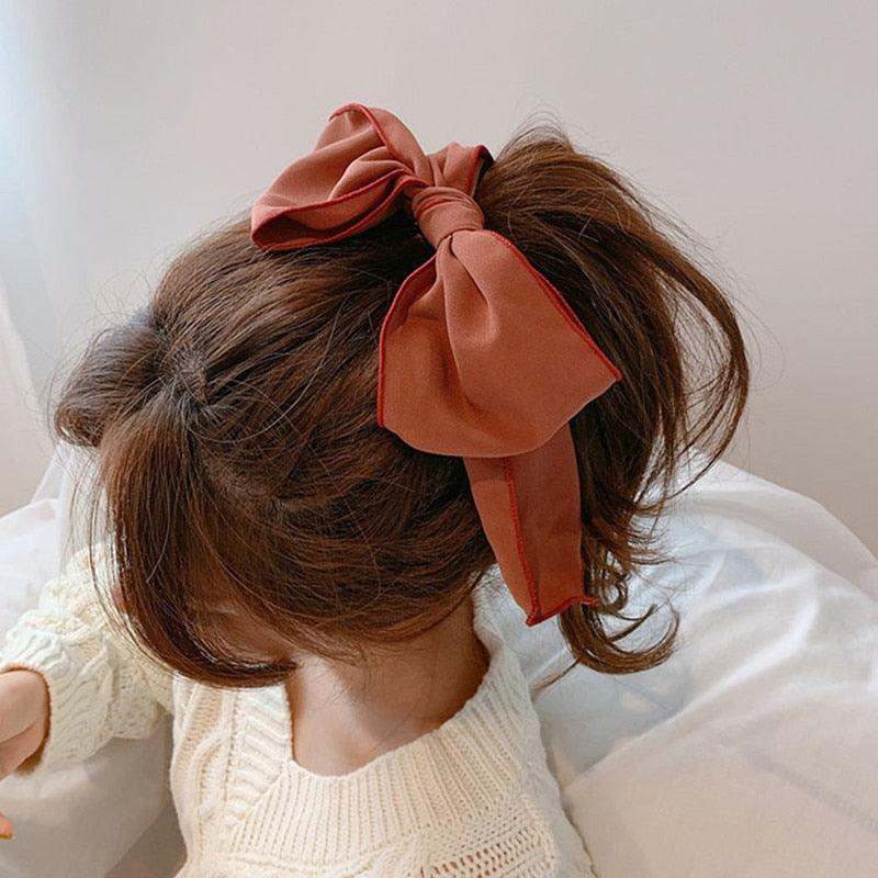 Rust-colored bowknot hair scrunchie with long tails on a ponytail