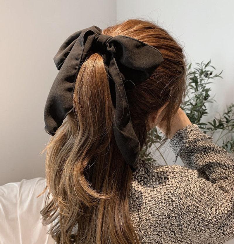 Black satin bow hair scrunchie with elastic hair band on long hair