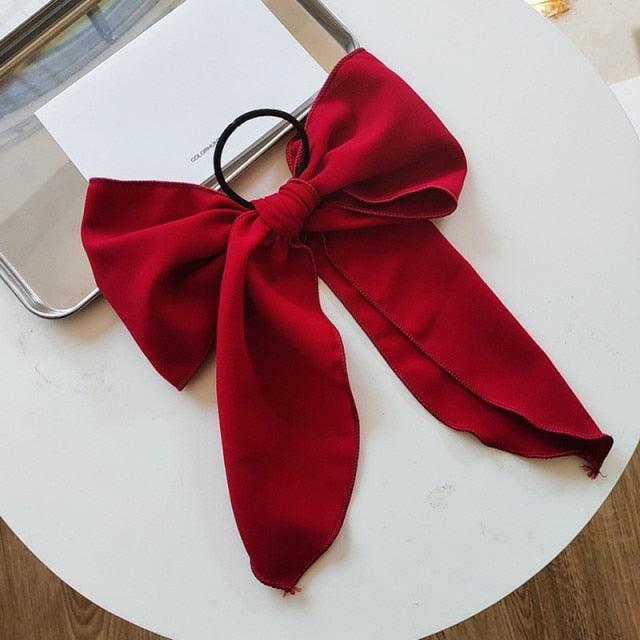 Red satin bowknot hair scrunchie with oversized bow and ribbon tails.