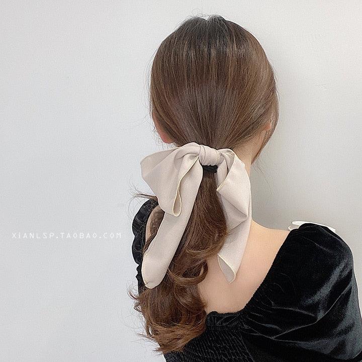 Beige bowknot hair scrunchie with long ribbon tails and elastic band.