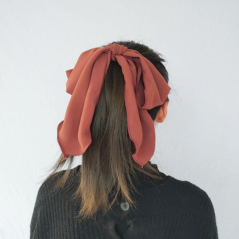 Rust bowknot hair scrunchie with gathered bow and long tails on hair