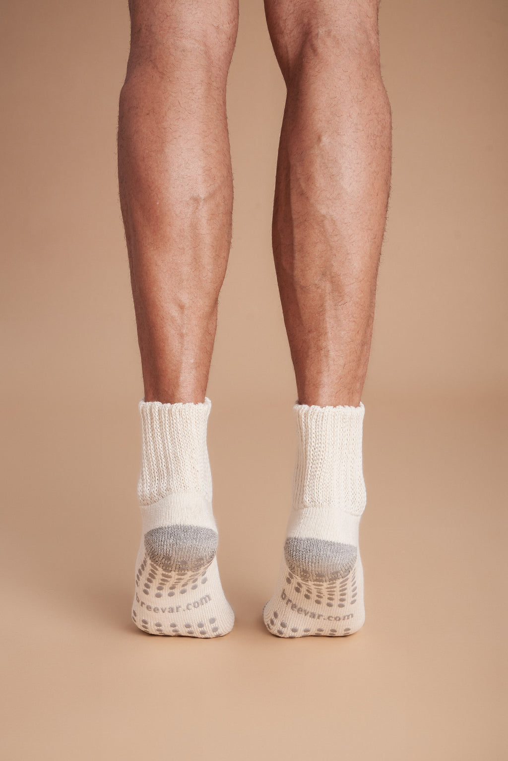 Men's crew socks on feet, off-white with gray toes and non-slip grip