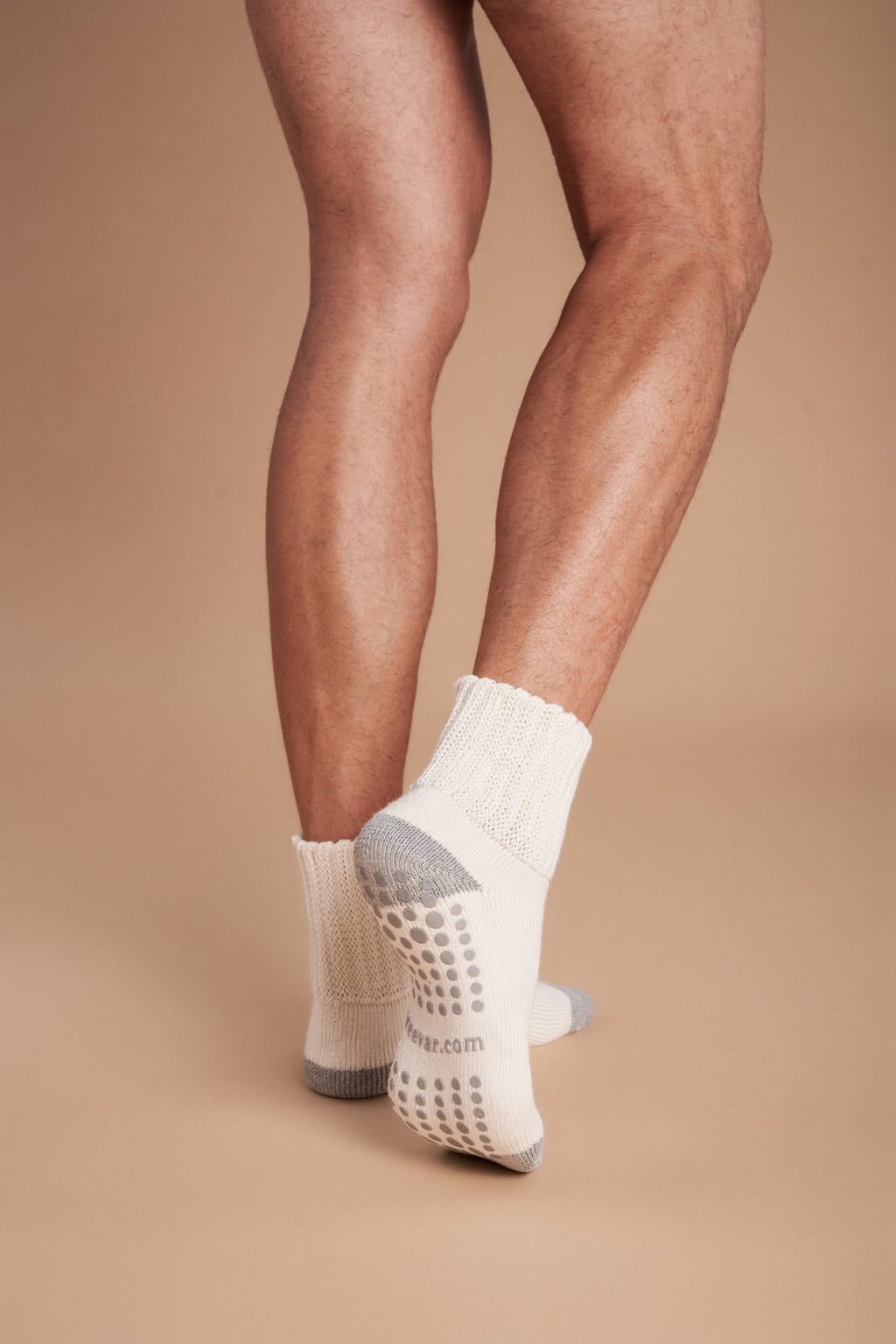 Men's crew socks on feet, off-white with gray heel and dotted non-slip sole