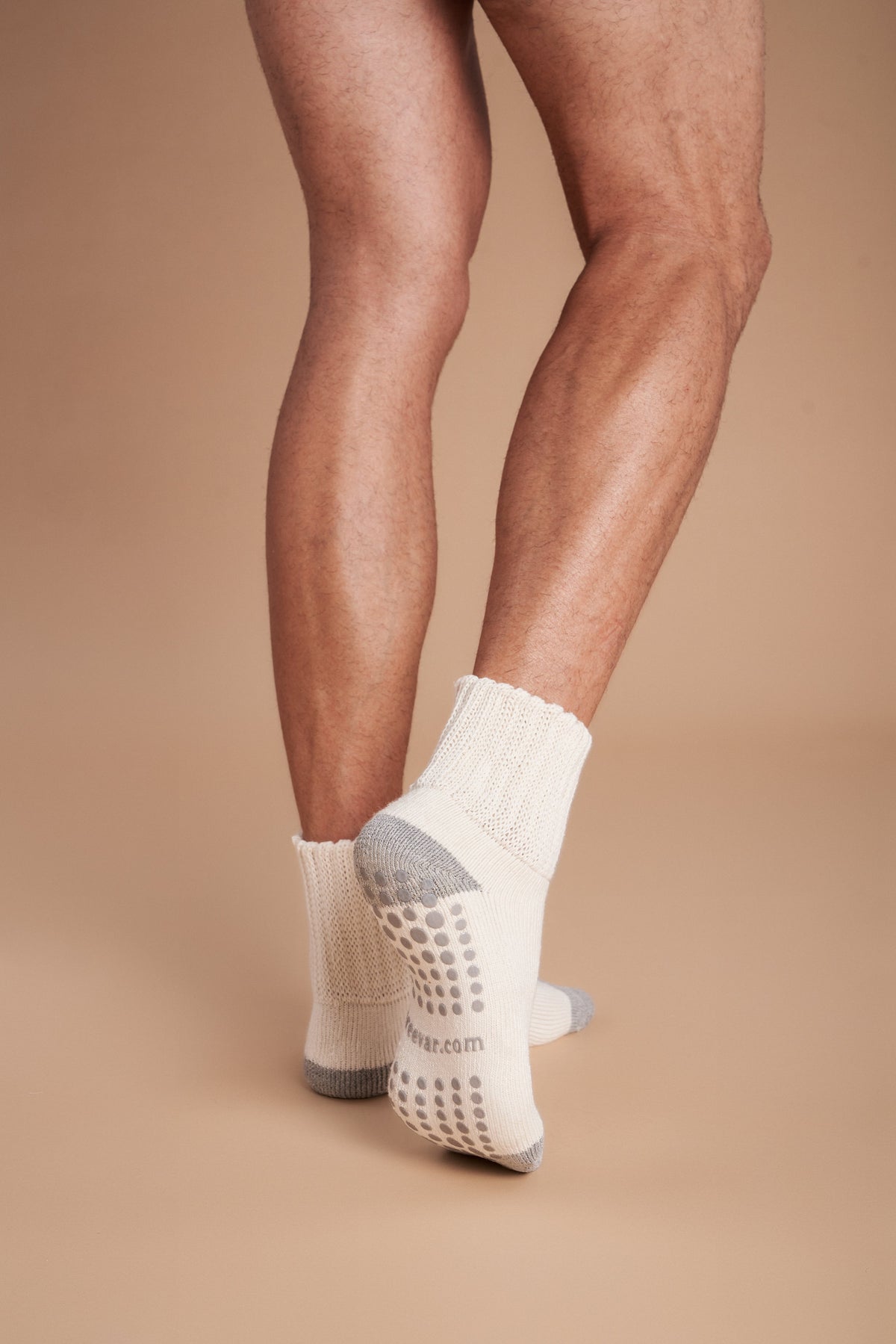 Men's crew socks on feet, off-white with gray heel and dotted non-slip sole