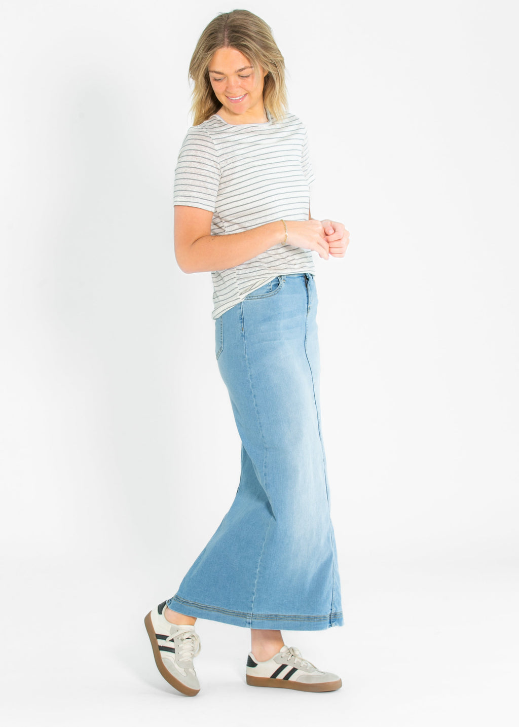 Light wash denim maxi skirt with fitted waistband and flared hem, worn