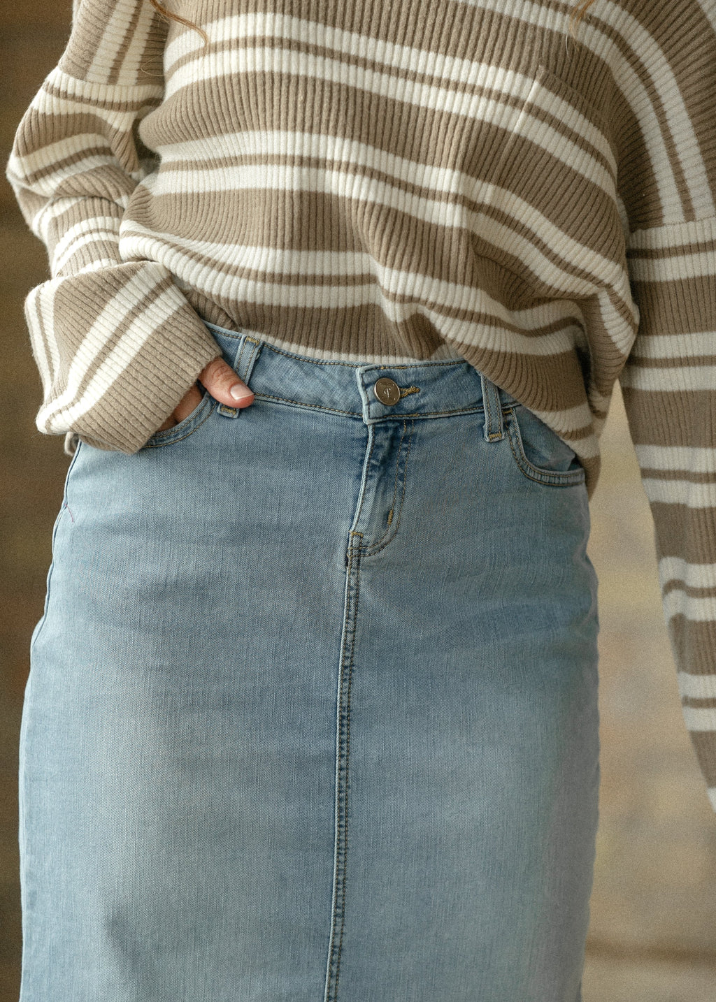 Light wash denim maxi skirt close-up with button closure and front seam