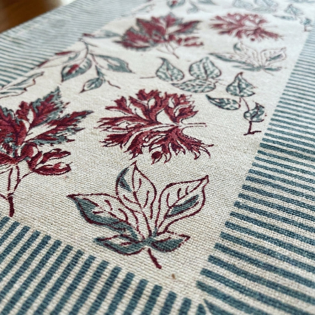 Close-up of leaf-printed cotton runner with red and teal foliage on cream