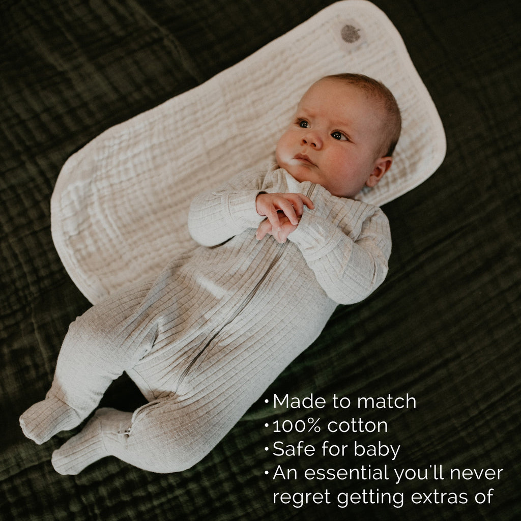 White muslin burp cloth draped over baby in textured fabric, rounded folded corners
