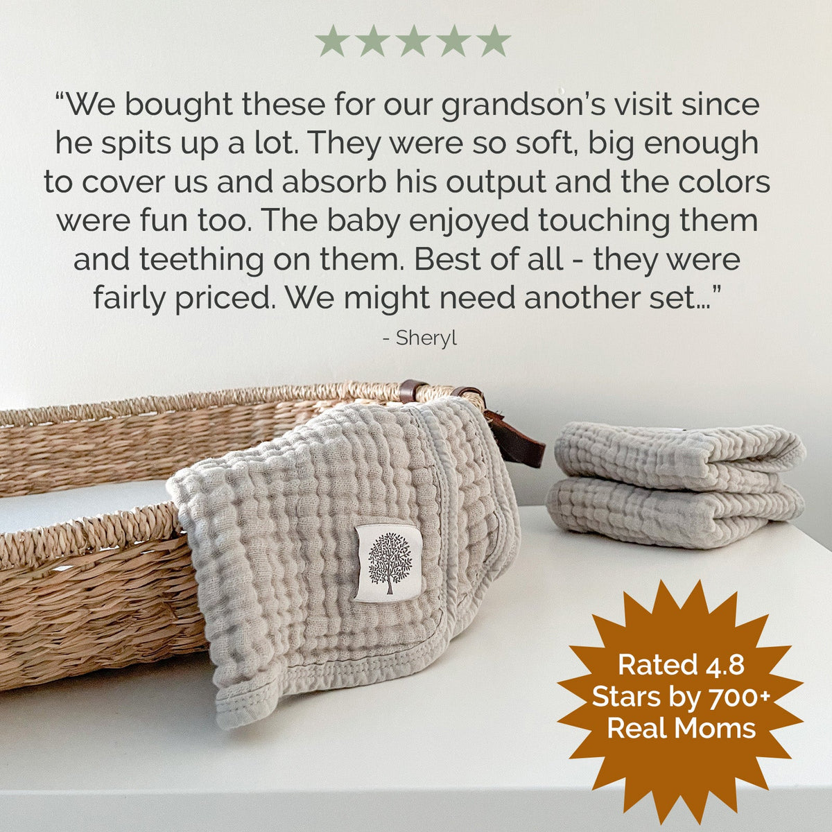 Folded white muslin burp cloths with tree patch, stacked in basket