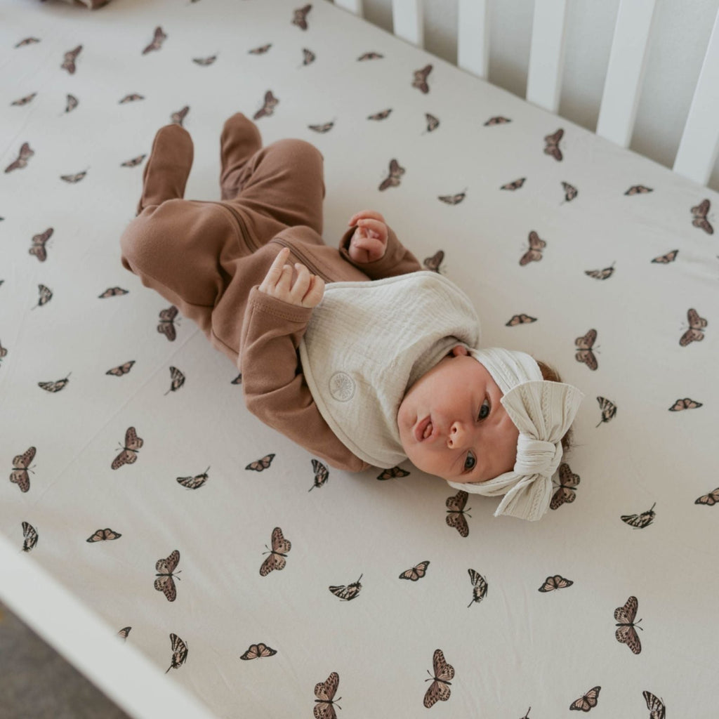 White crib sheet with small brown animal print, laid across a crib mattress