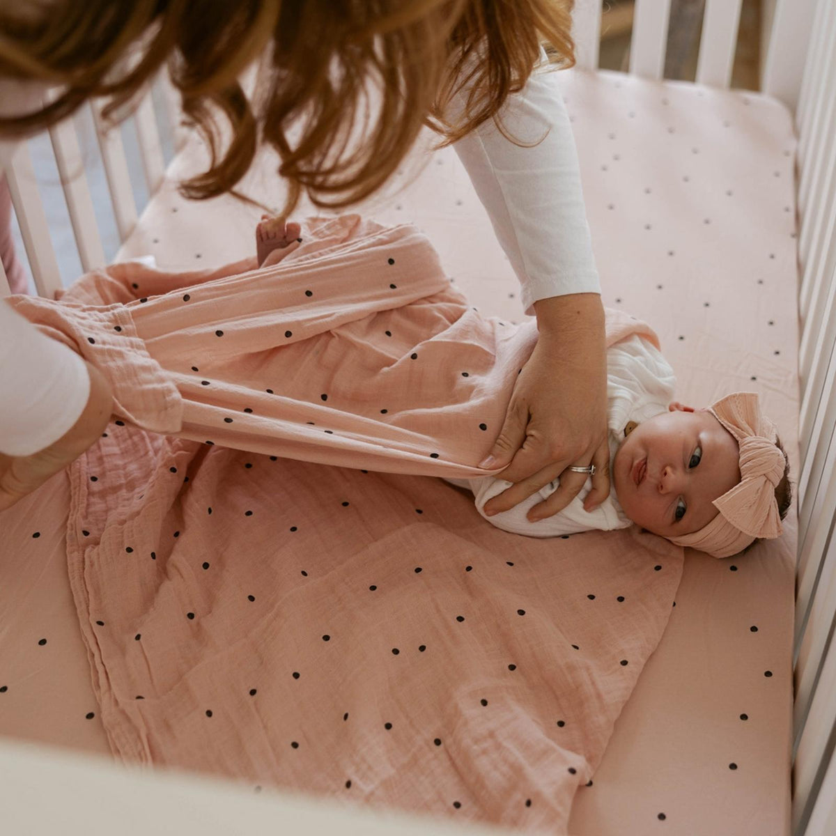 Butterfly swaddle set with peach dot and butterfly print blankets on a baby