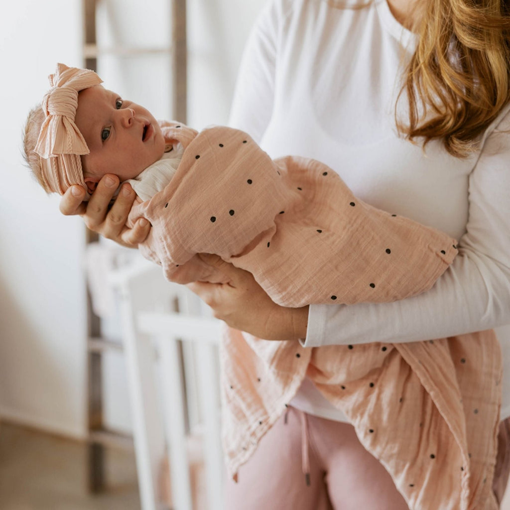Butterfly swaddle swaddled baby in peach dot muslin with matching hat