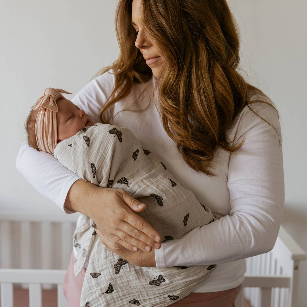 Butterfly swaddle blanket with allover butterfly print worn by a parent