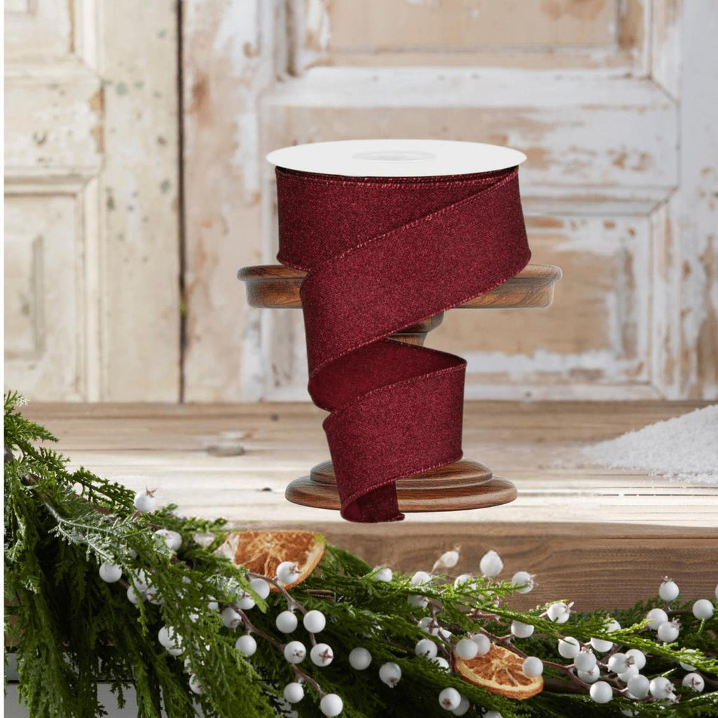 Burgundy glitter ribbon spool with neatly stacked wide ribbon loops