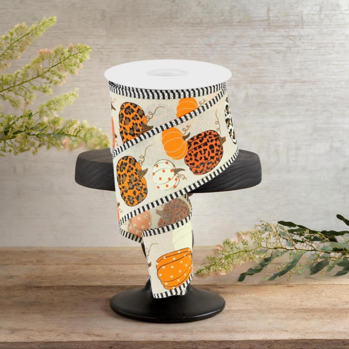 Cream ribbon spool with orange pumpkin and leopard motifs; black-and-white striped edging.