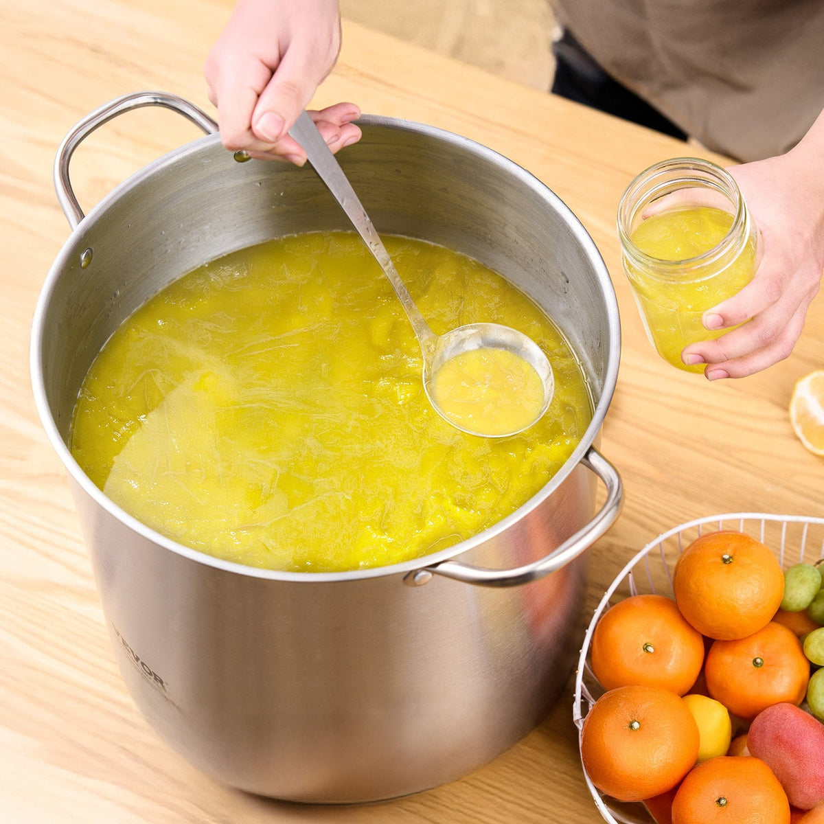 Stainless steel canning pot with yellow canning liquid and jars on countertop