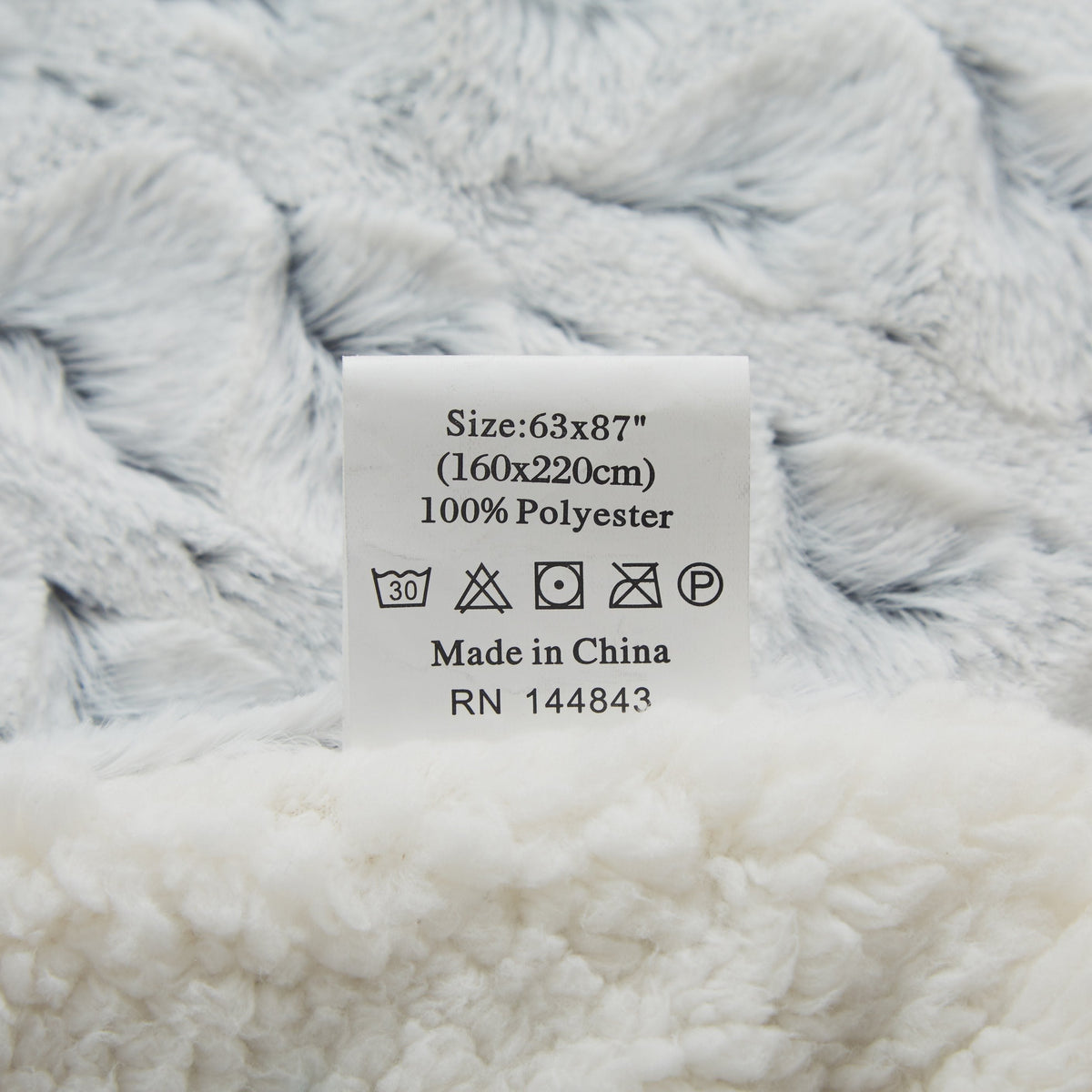 Faux fur throw blanket showing size and care label