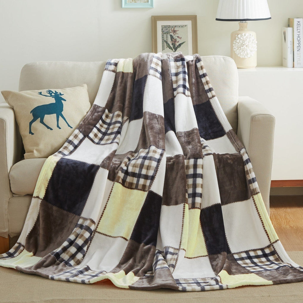 Patchwork plaid throw blanket draped over sofa in brown, cream, and navy